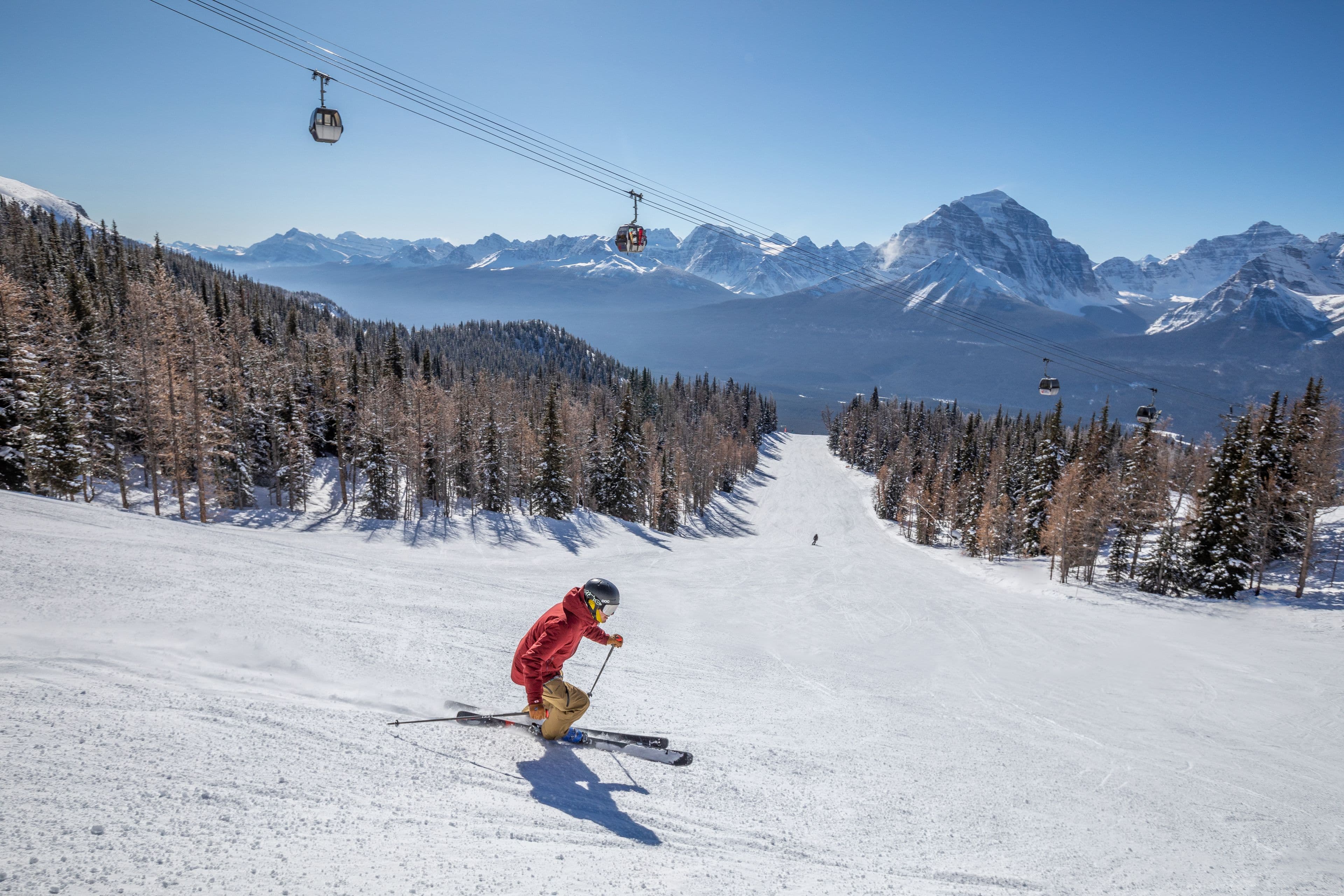 A skier skiing down an run under a chairlift, at Lake Louise Ski Resort in Banff National Park