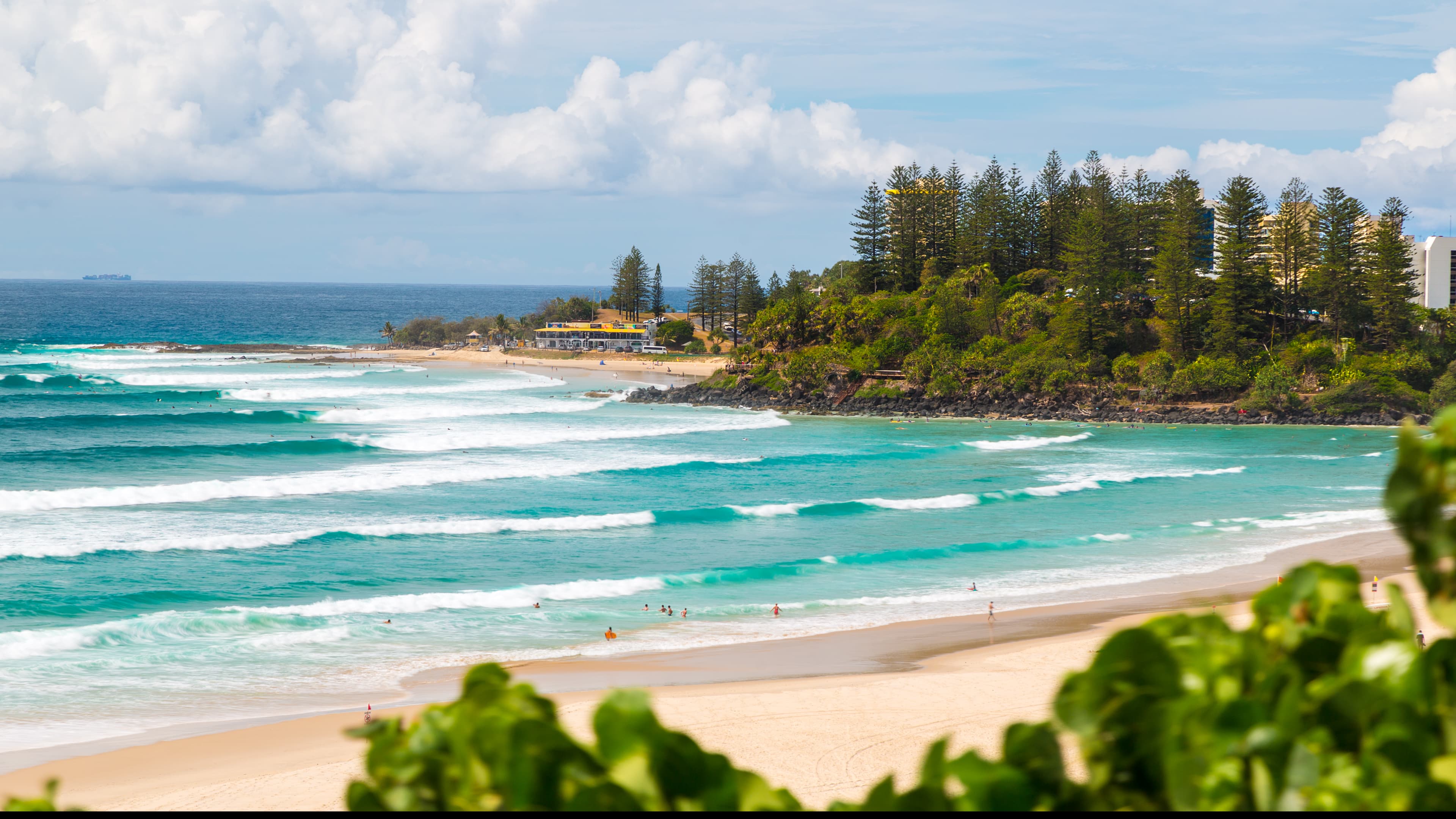 Surfers and swimmers in the waves at Snapper Rocks and Rainbow Bay beaches